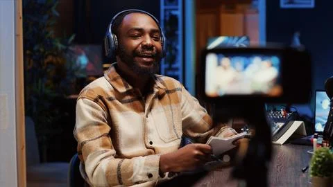 Man recording interview with professional camera in studio, reviewing notes to Fotos de archivo