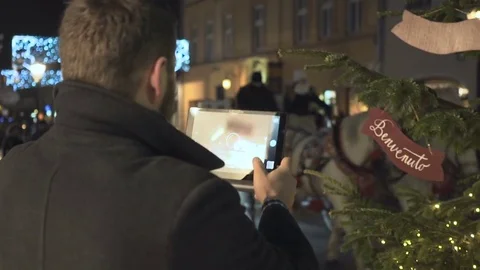 Man recording passing cab by tablet app, night, christmas, steadicam Vidéo 72782185