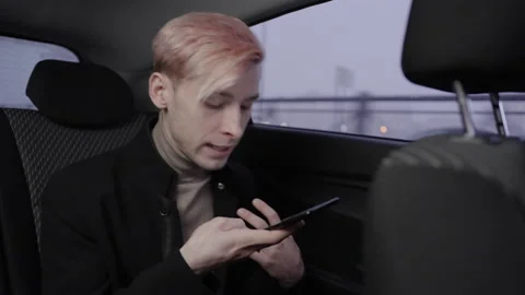 A man records an angry audio message on a smartphone in a taxi. 動画素材 196100901