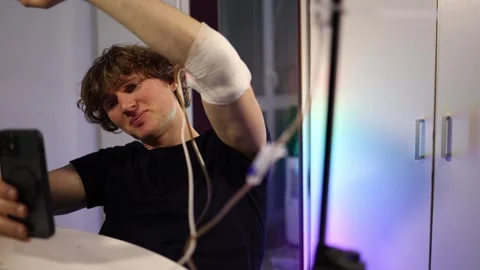 Man records selfie while checking bandaged arm and wearable health sensor Stock Footage 324444340