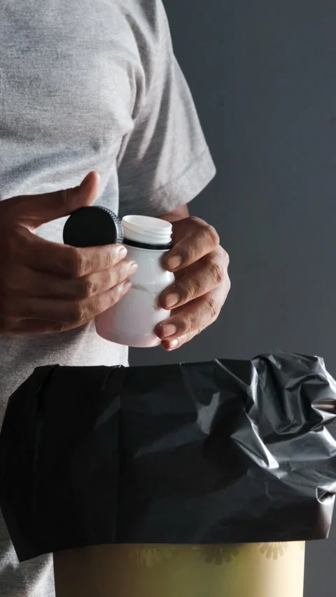 Man recovering from illness throwing away unused medication and pills Stockbeeldmateriaal 346577568