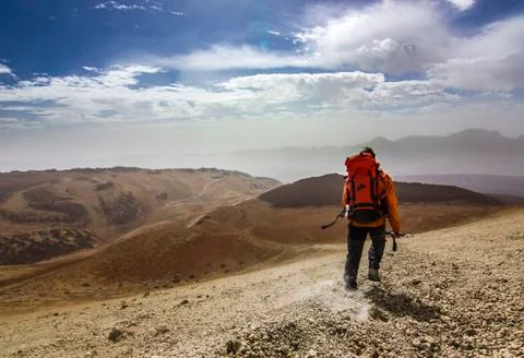Man with red backpack on rocky path in desert Stock Photos