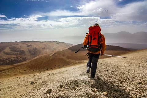 Man with red backpack on rocky path in desert Stock Photos