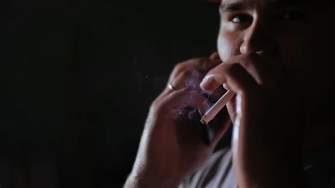 A man in a red baseball cap smokes a cigarette. Stock Footage 77195003