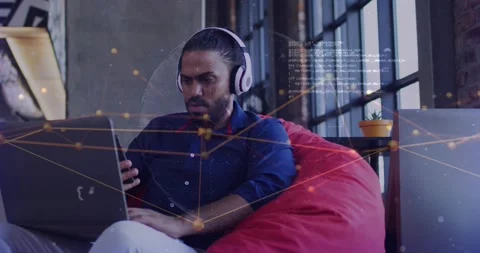 Man on red bean bag tapping phone, typing laptop, causing animated node Stock Footage 333903010