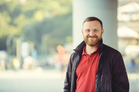 A man with a red beard, dressed in a red gaiety in the city. Happy and health Stock Photos