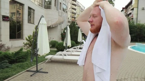Man with red beard drying himself off with a towel after swimming in the pool 動画素材 150268235