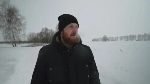 Man with red beard walks across field and smokes cigarette Stock Footage 258580698
