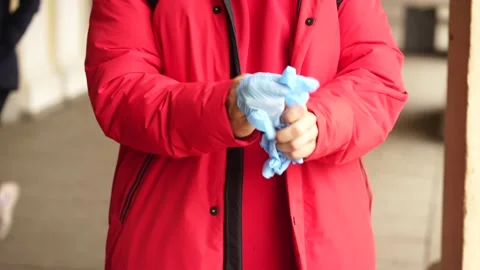 A man in red clothes puts on protective gloves on the street 스톡 동영상 136234574