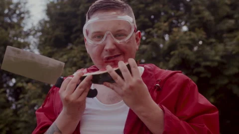 Man in a red coat eating some watermelons in his garden Stock-Footage 258310880
