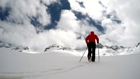 Man in a red coat hikes across snowy Antarctic mountains under winter clouds Video stock 339353249