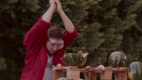 Man in a red coat slicing some watermelons in his garden Stock-Footage 258313176