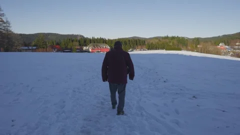 A man in a red coat walks across a snowy field Stock Footage 304522552