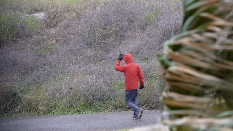 Man in red coat walks in windy tropical storm on Amelia Island in Florida Stock Footage 129267287