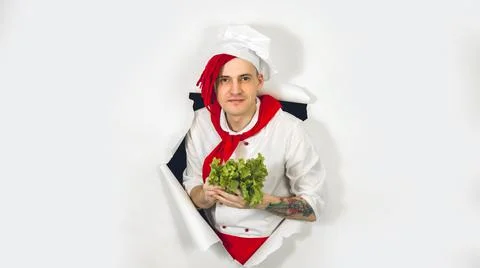 Man with red dreadlocks holds it in his hand lettuce leaves. Cook in white ap Stock Photos