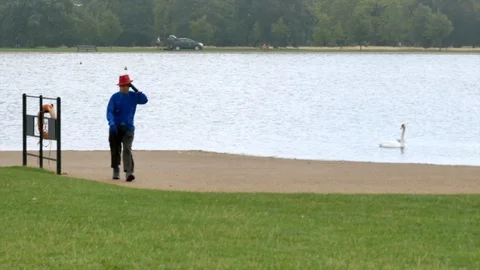 Man In The Red Hat And Blue Coat Walks In The Rain In Hyde Park Stock Footage 104594643