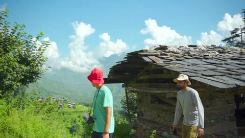 A man in a red hat explores a scenic mountain village in a about Jibhi, India Stock Footage 333235815