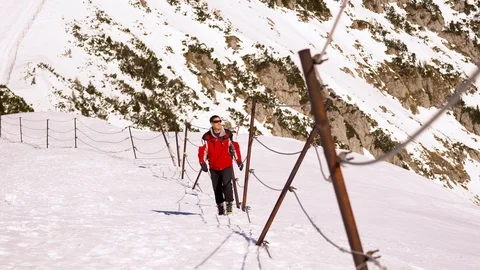 A man in red jacket and sunglasses hiking in snowy mountains Stock Footage 103152402