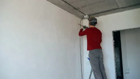 A man in a red jacket is chasing the wall with a puncher. Stock Footage 150138078