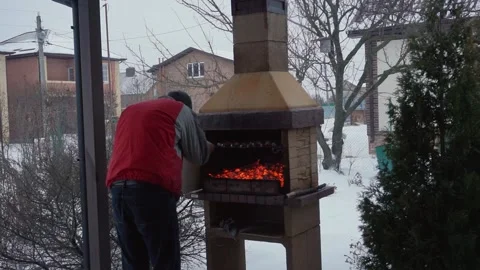 Man in a red jacket fries meat on the grill in winter in the oven on the veranda Stock Footage 148553951