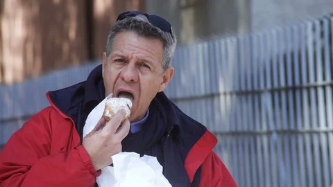 A man in a red jacket happy to have a cake binier on the street Vidéo 100948385