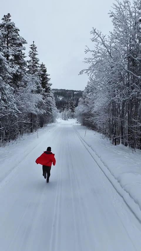 Man in red jacket running through snowy forest road, Norway Vídeos de archivo 345093970