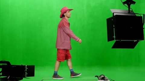 A man in red jacket, shorts and pink cowboy hat walks on chroma key background Stock Footage