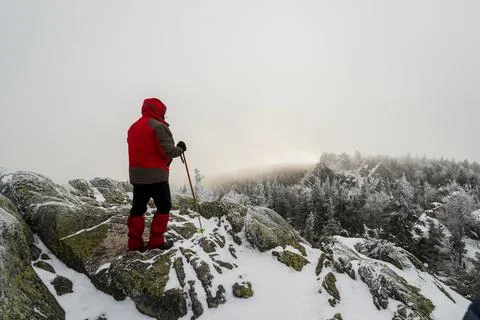 A man in a red jacket stands on top of a cliff Stock Photos