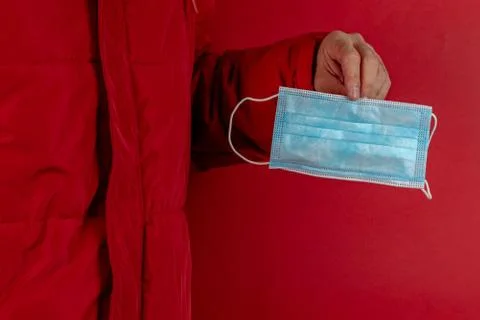Man in red jacket is using a protective mask against corona virus on red back Stock Photos
