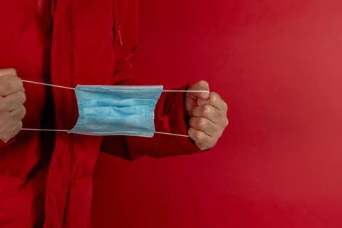 Man in red jacket is using a protective mask against corona virus on red back Stock Photos