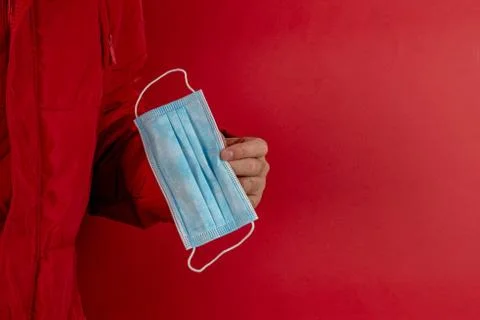 Man in red jacket is using a protective mask against corona virus on red back Foto stock