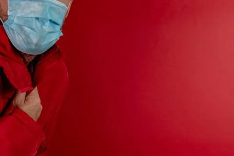 Man in red jacket is using a protective mask against corona virus on red back Stock Photos