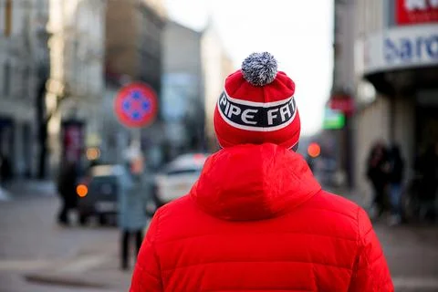 Man in red jacket walking through city center Foto stock