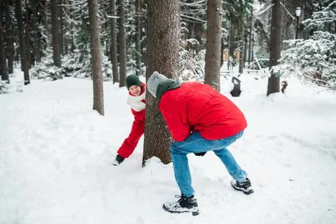A man in a red jacket in a winter forest playing catch-up with his nephew, a boy Stock Photos