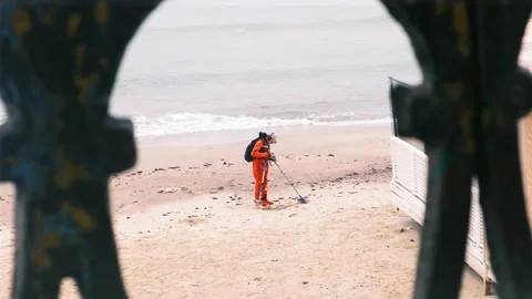 Man in red jumpsuit looking for the lost luxuries with electronic metal detector Stock Footage 164918104