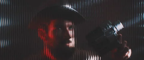 Man in red lights looking through clear panel with vintage camera Stock Footage 203571792