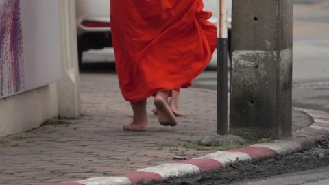 A man in a red robe walks barefoot on a brick sidewalk Stock Footage 289321659
