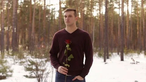 A man with a red rose in the winter forest.Slow motion Stock Footage 73589963