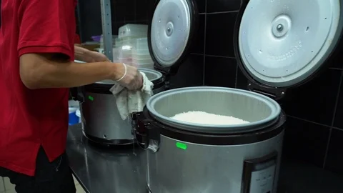 Man in a red shirt pulls out pan of hot rice. Concept of cooking in restaurants. Video stock 119979174