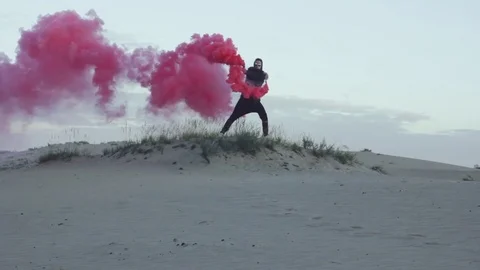 Man with red smoke in desert Stock Footage 77583191