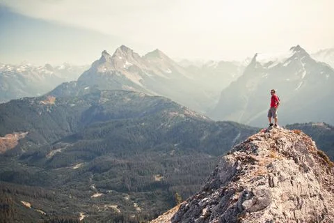 Man in red standing on summit looking out at the view. Stock Photos
