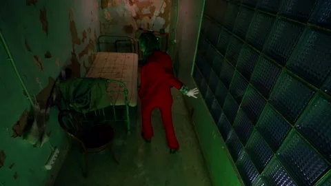A man in a red suit is freaking out in a ragged little dirty room. green light Vídeo Stock 166163541