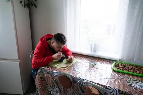 A man in a red sweatshirt eats soup at a table covered with a patterned table Stock Photos