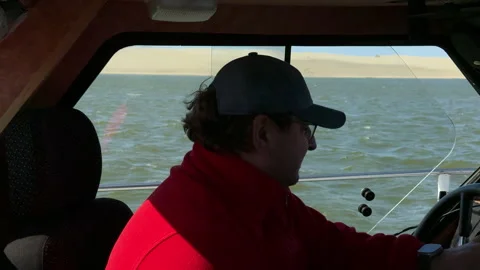 Man in red sweatshirt steering small boat at sea Stock Footage 310445971