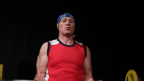 A man in a red T-shirt does a Bicep curls with a barbell.Isolated on a black Stock Footage 124897646