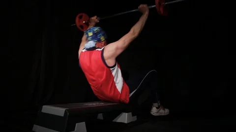 Man in a red t-shirt performs sit-ups with barbell.Abdominal crunches.Isolated Stock Footage 125006788
