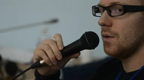 A man with a reddish beard gestures and speaks into the microphone Stock Footage 64232416