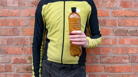 The man reduces brown plastic bottle, releases air before disposal Stock Footage 106632810