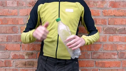 The man reduces white plastic bottle, releases air before disposal Stock Footage 106632816