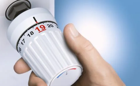 Man reducing energy consumption by setting thermostat temperature to 19 degre 库存照片